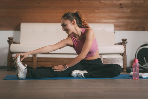 Belle jeune femme faisant des exercices d'étirement à la maison.