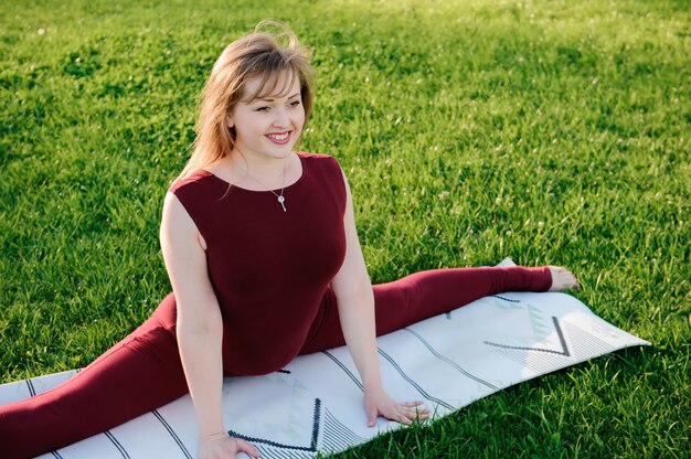 Belle jeune femme faisant des exercices de yoga dans le parc