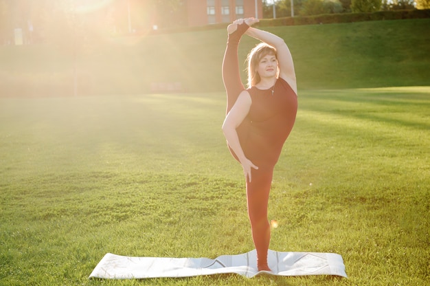 Belle jeune femme faisant des exercices de yoga dans le parc