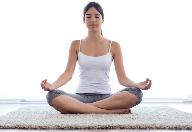 Belle jeune femme faisant des exercices de yoga à la maison.