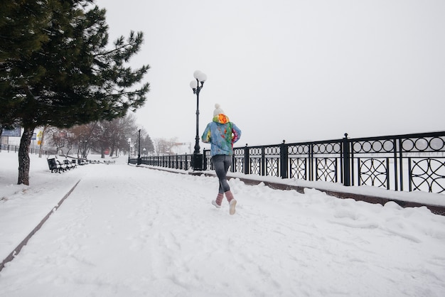 Une belle jeune femme fait du jogging un jour givré et neigeux. Sports, mode de vie sain