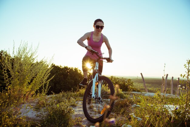 Une belle jeune femme fait du vélo le jour de la nature