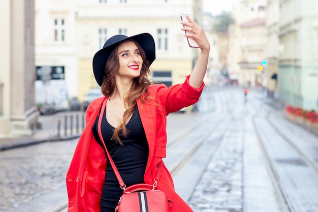 Belle jeune femme fait selfie dans la ville.