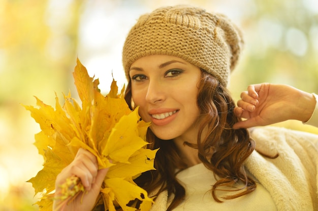 Belle jeune femme avec des feuilles allongées sur l'herbe dans le parc en automne