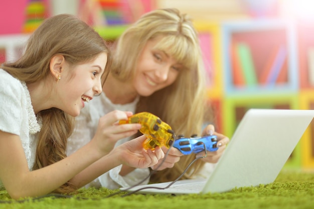 Belle jeune femme et fille utilisant un ordinateur portable et jouant à des jeux