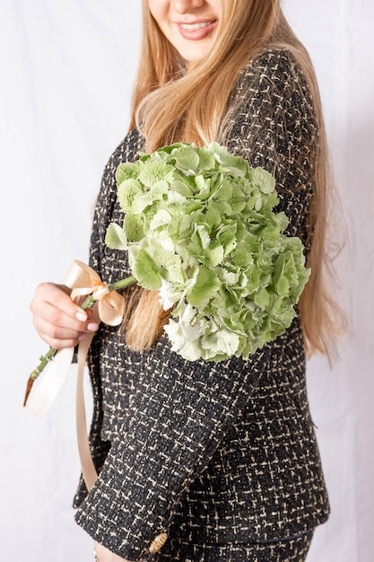 Belle jeune femme avec une fleur sur une veste en tweed