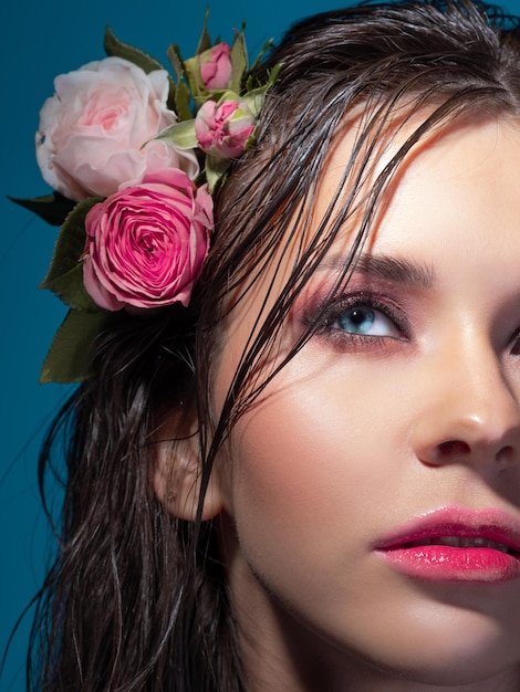 Une belle jeune femme avec des fleurs roses dans ses cheveux mouillés portrait d'une belle brune aux perf...