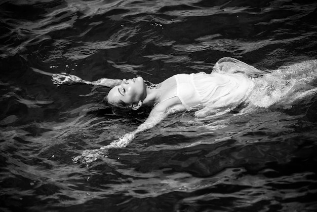 Belle jeune femme flottant dans l'océan ou l'eau de mer se détendre et prendre soin d'elle-même fashion por