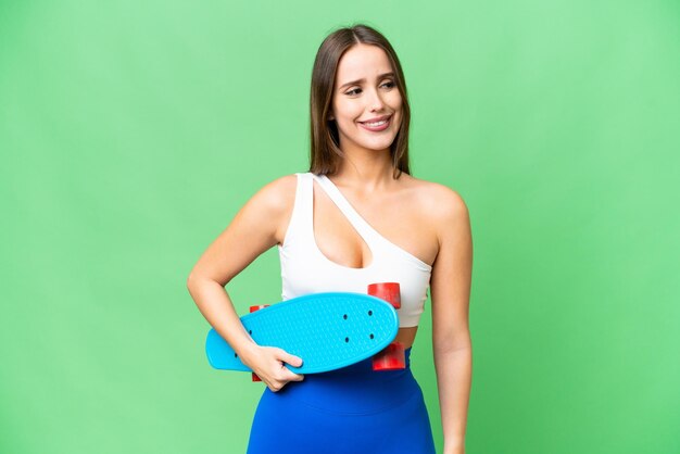 Belle jeune femme sur fond isolé chroma key avec un skate