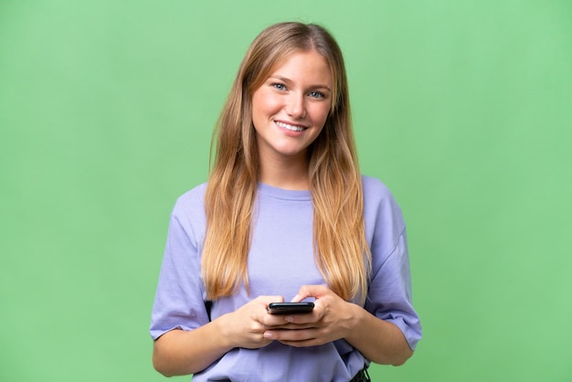 Belle jeune femme sur fond isolé envoyant un message avec le mobile