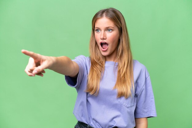 Belle jeune femme sur fond isolé pointant vers l'extérieur