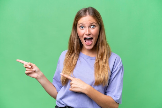 Belle jeune femme sur fond isolé surpris et pointant du côté