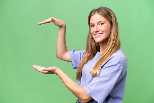 Belle jeune femme sur fond isolé tenant un espace de copie pour insérer une annonce