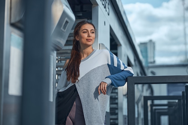 Belle jeune femme en forme avec un regard rêveur debout devant la porte d'entrée