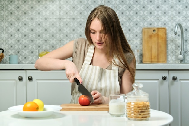 Belle Jeune Femme Avec Des Fruits Dans La Cuisine, Femme Assise à Table Et Couper Des Pommes