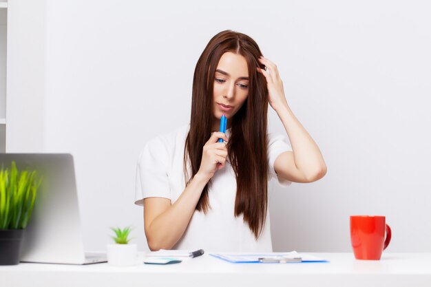 Belle jeune femme gestionnaire travaillant avec des documents au bureau