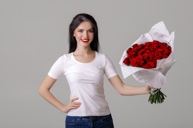 Belle jeune femme avec un grand bouquet de roses rouges