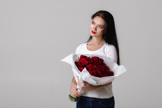 Belle jeune femme avec un grand bouquet de roses rouges