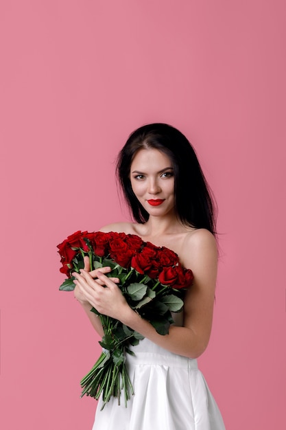 Belle jeune femme avec un grand bouquet de roses rouges