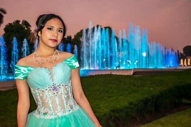 Belle jeune femme habillée en costume de princesse dans un paysage de bassins aux lumières colorées