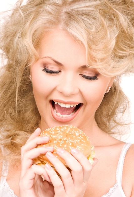 Belle jeune femme avec hamburger sur mur blanc