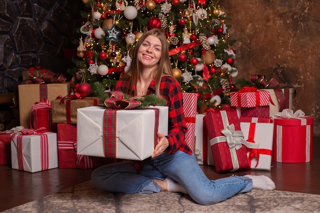 belle jeune femme heureuse à la maison près de l'arbre de noël à noël