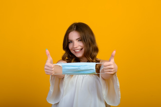 Belle jeune femme heureuse avec un masque dans les mains. Virus COVID et pollution atmosphérique. Récupération d'une maladie, fin de l'épidémie.