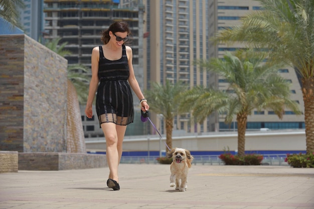 belle jeune femme heureuse en robe noire avec un mignon petit chien chiot s'amuser dans la rue