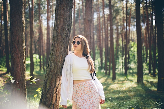 Une belle jeune femme hippie se promène dans la forêt d'été, rit, danse et profite de la vie et de la nature