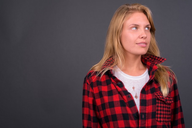 Belle jeune femme hipster aux cheveux blonds contre le mur gris