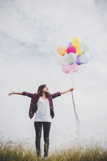 Belle jeune femme hipster tenant avec des ballons colorés en plein air, Liberté jouissent de la nature. Concept de style de vie féminin.