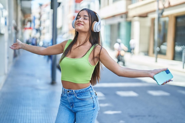 Belle jeune femme hispanique écoutant de la musique et dansant dans la rue