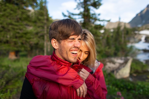 Belle jeune femme et homme marchent dans un câlin et s'embrassent dans la nature de la montagne au soleil