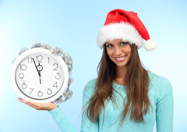 Belle jeune femme avec horloge, sur une surface bleue