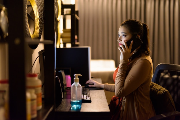 Belle jeune femme indienne parlant au téléphone tout en travaillant à la maison tard dans la nuit