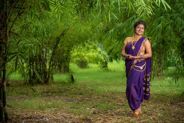 Belle jeune femme indienne en sari traditionnel posant à l'extérieur