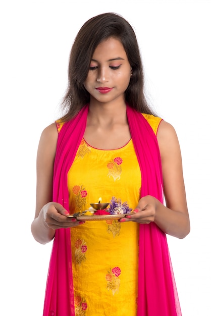 Belle jeune femme indienne tenant pooja thali ou effectuant un culte sur blanc