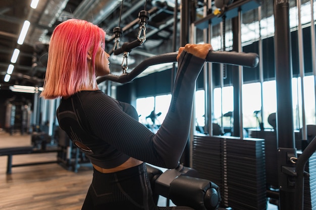 Belle jeune femme instructrice de fitness s'entrainant et la pompant dans la salle de gym