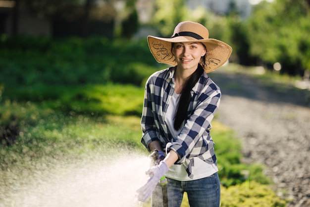 Belle jeune femme jardinier arrosant le jardin en chaude journée d'été.