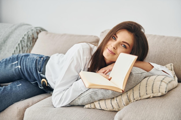 Belle jeune femme en jeans et chemise blanche est à la maison