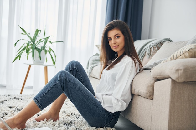 Belle jeune femme en jeans et chemise blanche est à la maison