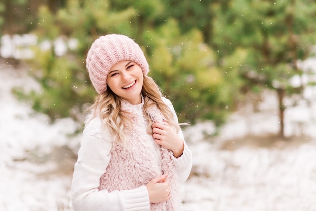 Belle jeune femme en jeans et veste rose en forêt d'hiver