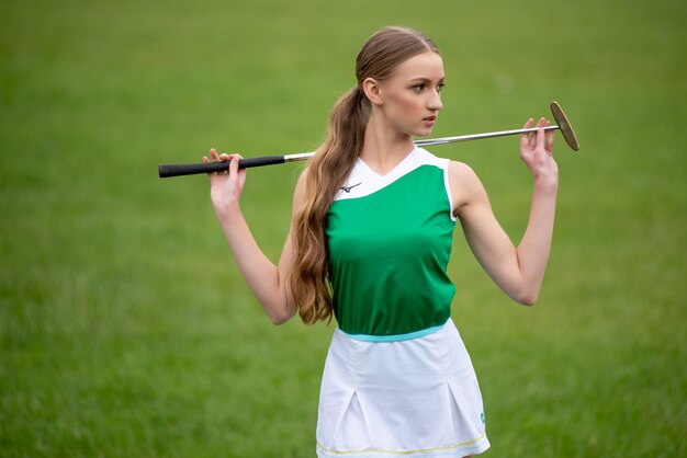 Belle jeune femme jouant au golf sur l'herbe verte