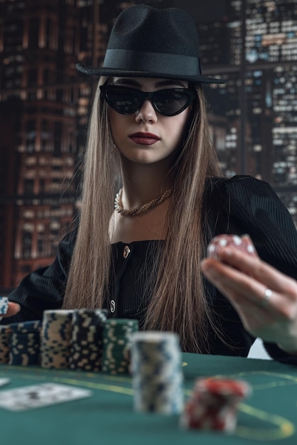 Belle jeune femme jouant au poker et tenir des jetons fait un pari relance