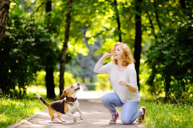 Belle jeune femme jouant avec un chien Beagle dans le parc de l&#39;été