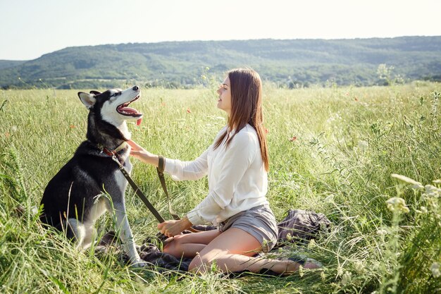 Belle jeune femme jouant avec un chien husky drôle à l'extérieur au parc