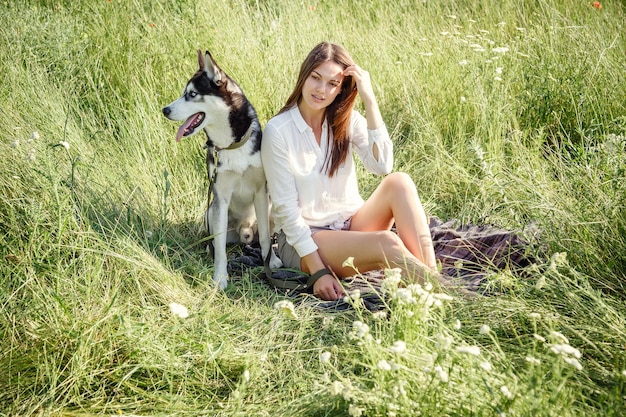 Belle jeune femme jouant avec un chien husky drôle à l'extérieur au parc