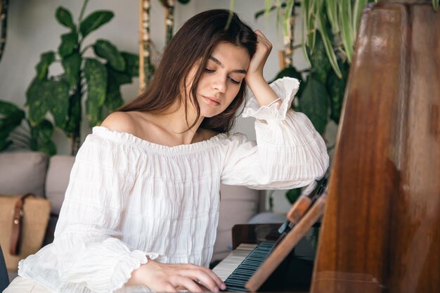 Une belle jeune femme joue du vieux piano en bois