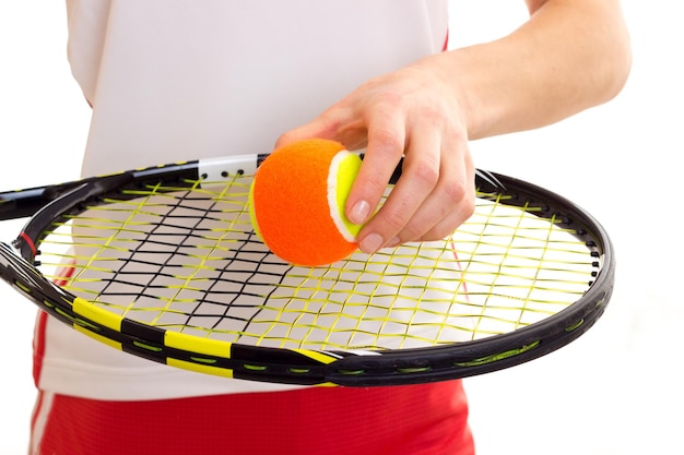 Belle jeune femme en jupe rouge avec queue de cheval châtaigne tenant une raquette de tennis et une balle jaune