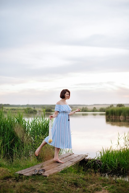 Belle jeune femme sur le lac au coucher du soleil